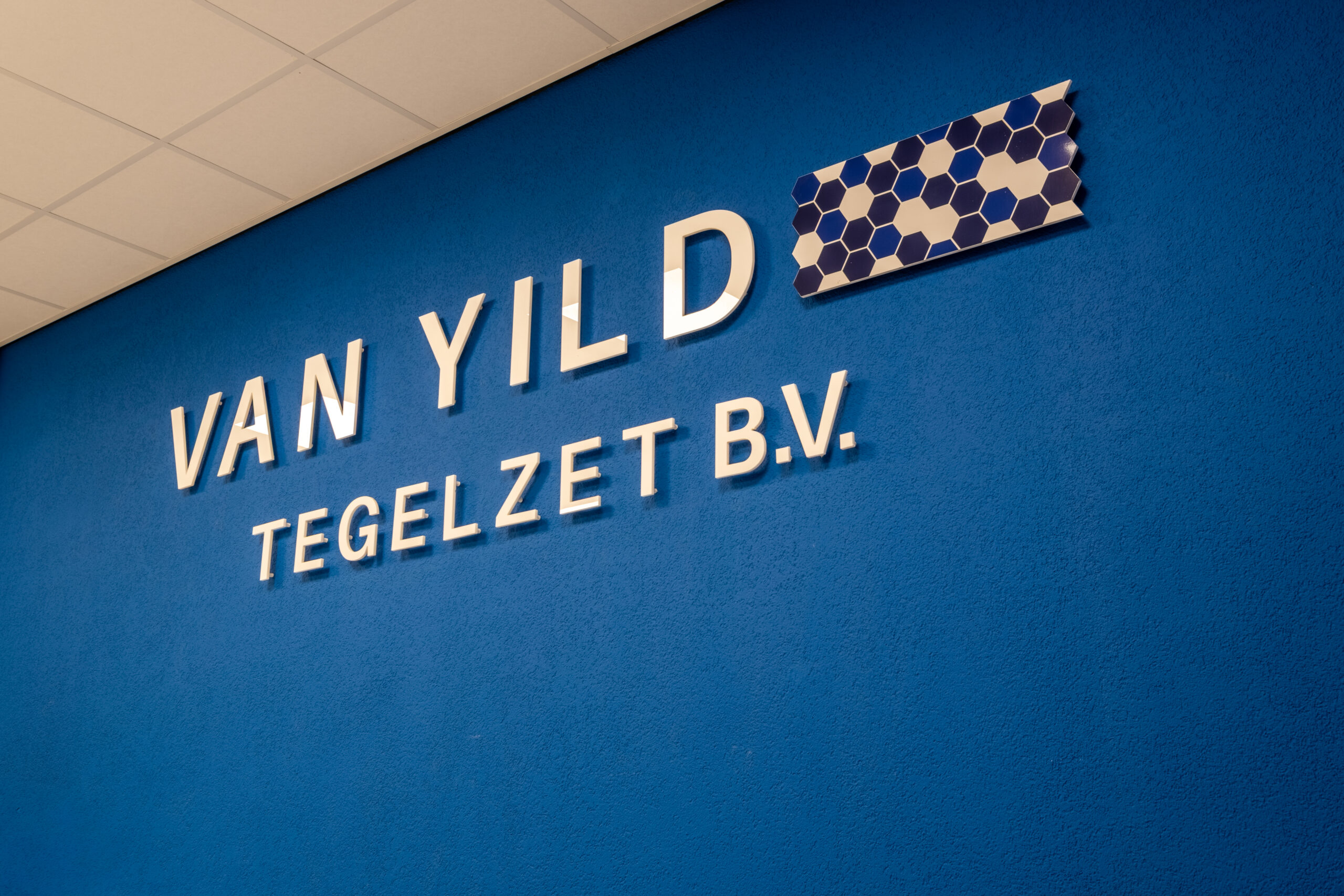 Blauwe wand in de showroom met de naam Van Yild Tegelzet B.V.